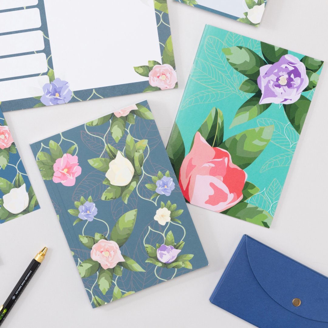 2 B5 and 2 A5 Notebooks are lying slightly on top of each other.  They are on a lilac desk with pens, keyboard and other desk items around them.