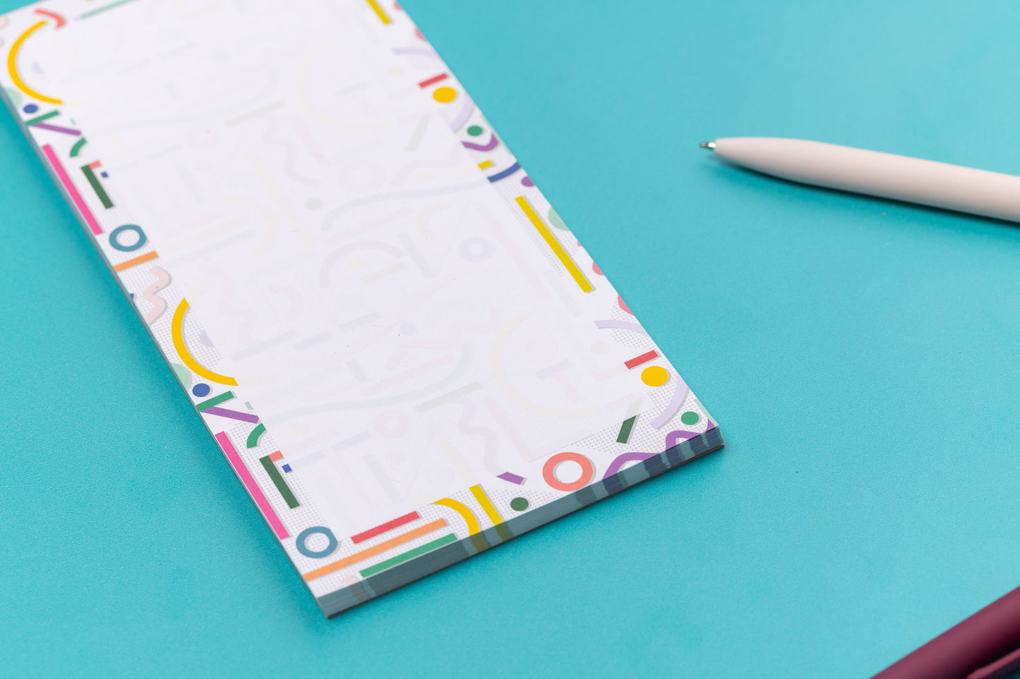 More detailed view of the Cutouts List pad is on a teal desk, with a white pen to its right.