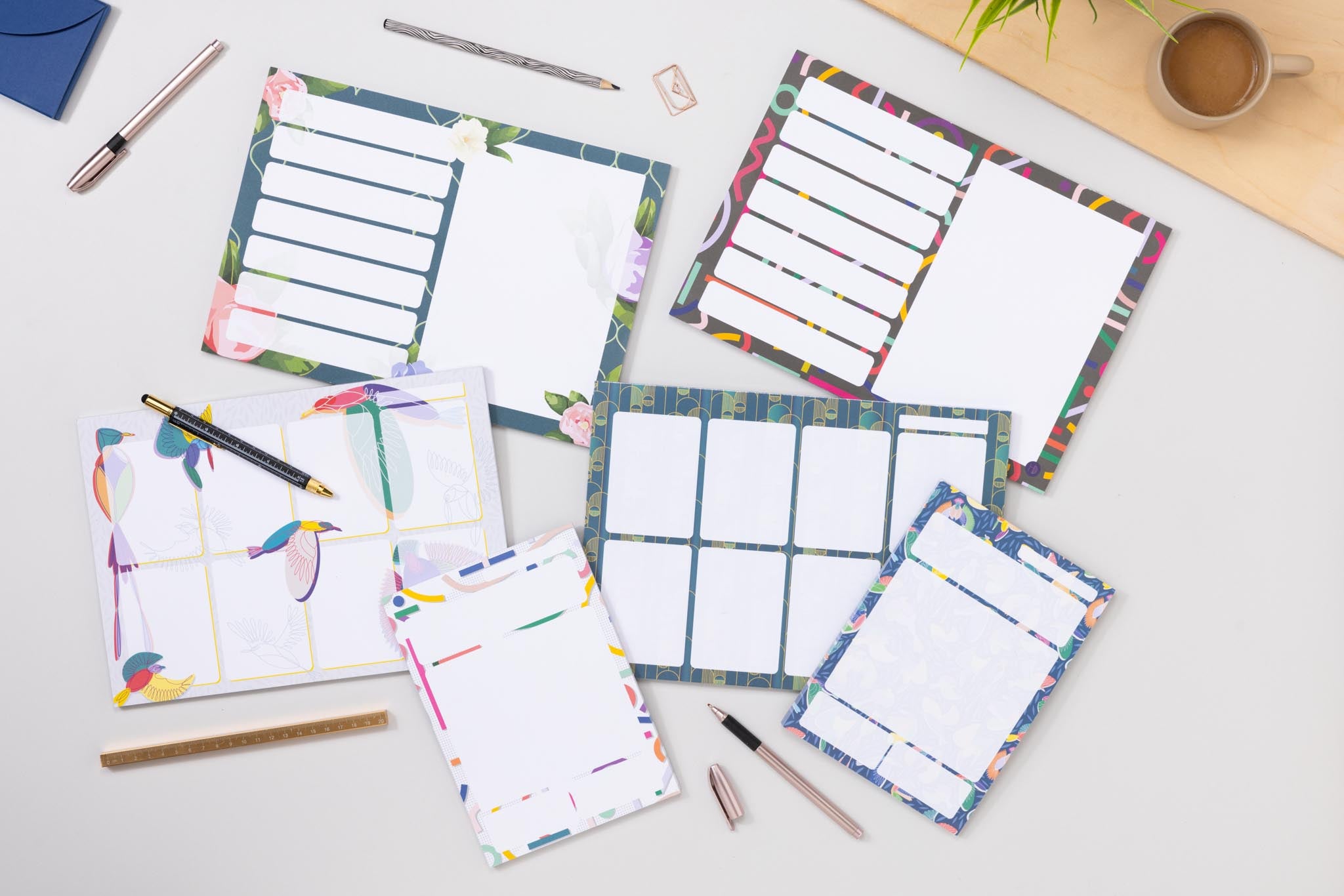 Colourful planner notepads with various designs on a desk with stationery items.