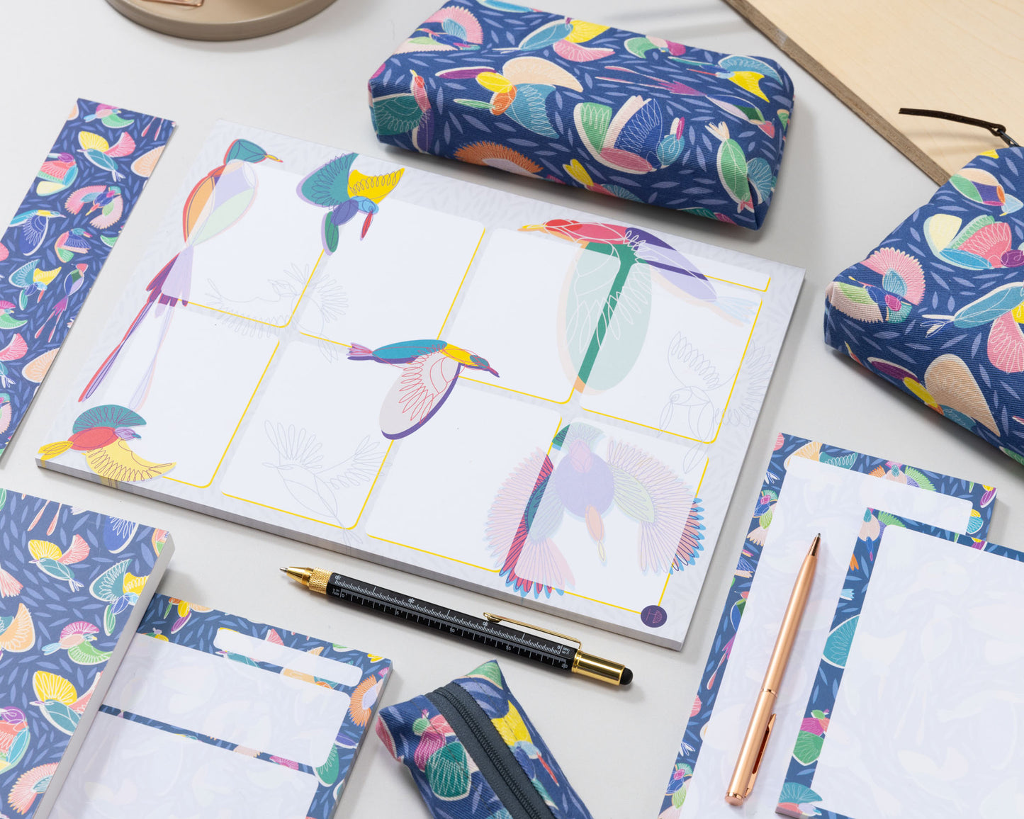 Colourful Stationery set with the Paradise Pattern on a desk with pens and coffee cup.