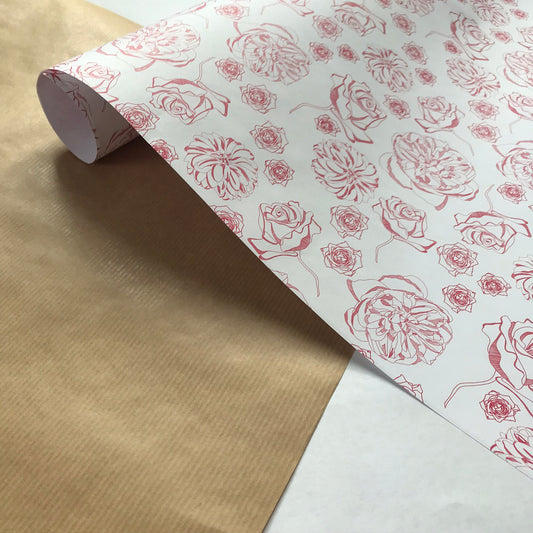 Spring Forward wrapping paper - white background with dark pink line-drawn floral motifs - is on a table, with one end rolled slightly whilst the other has unravelled on the table top.