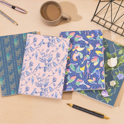 Colorful patterned notebooks on a wooden surface with a cup of coffee and stationery items.