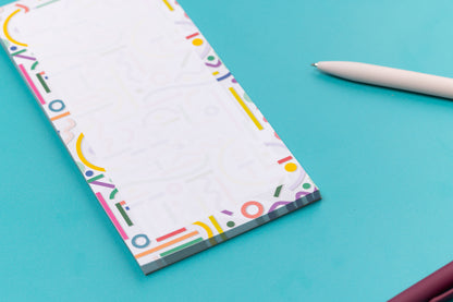 More detailed view of the Cutouts List pad is on a teal desk, with a white pen to its right. 