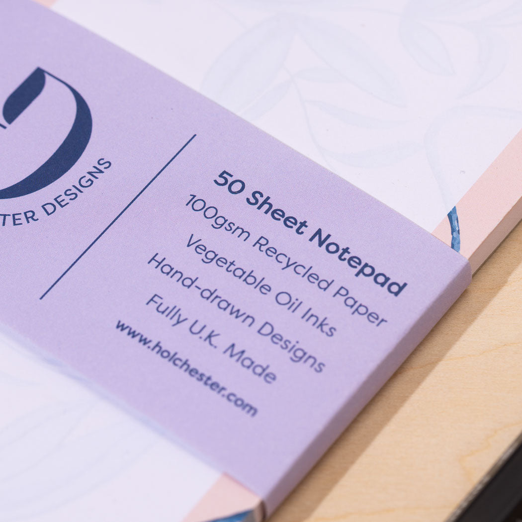 Branded purple belly band around a DL notepad with text about paper and print quality.