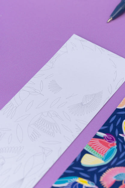 Two of the paradise double-sided bookmarks, on a lilac desk. The main focus is on the top of the monochrome side of the bookmark, with the blank circle for writing at the top of the marker.  The full-pattern side of the bookmark is in the bottom right corner slightly out of focus.